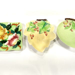 Puede incluir: Tres platos decorativos de cerámica con diseños florales y de hojas. Los platos son verdes, amarillos y blancos con detalles pintados.