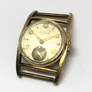 Op de afbeelding: Een gouden Longines polshorloge met een witte wijzerplaat en zwarte wijzers. Het horloge heeft een unieke, gebogen band.