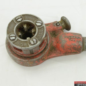 May include: A red and silver pipe threading tool with a 1/2 inch die. The tool is made in the USA and is labeled "RIDGID 0-R".