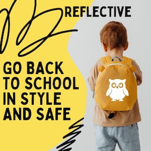 Peut inclure: Un enfant porte un sac à dos jaune moutarde avec un motif de hibou blanc. Le sac à dos a des oreilles d'ours et une queue. Le texte sur un fond jaune indique "GO BACK TO SCHOOL IN STYLE AND SAFE" et "REFLECTIVE".