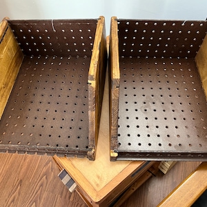 May include: Two open-top storage bins featuring dark brown pegboard panels with evenly spaced circular holes. The sides of each bin are constructed from stained wood with a visible grain, providing a sturdy frame for the perforated metal base.