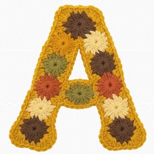 May include: A handcrafted, crocheted letter "A" in a warm color palette. The letter is made of individual floral granny squares in shades of mustard yellow, brown, orange, and cream. The edges are outlined in a darker mustard yellow.