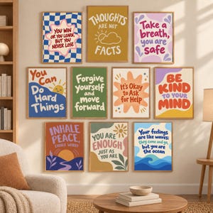 Könnte beinhalten: Eine Sammlung von elf rechteckigen Wandbildern mit motivierenden Zitaten und farbenfrohen grafischen Designs. Jeder Druck ist in hellem Holz gerahmt und zeigt positive Affirmationen wie You Win Or You Learn, Thoughts Are Not Facts und Be Kind To Your Mind, die in einem Raster an einer neutralen Wand angeordnet sind.
