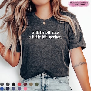 May include: Dark gray unisex t-shirt with the text "a little bit emo a little bit yeehaw" in a white, gothic font. The shirt is a Bella Canvas 3001. The shirt is a crew neck and has short sleeves.