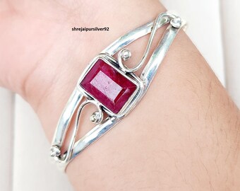 Puede incluir: Un brazalete de plata con una gran gema rectangular de color rojo intenso en el centro. El brazalete tiene un diseño calado con detalles en espiral. El texto "shrejaipursilver92" es visible.