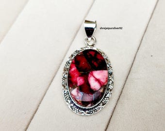 May include: Oval pendant with a silver-coloured frame. The pendant features a mosaic of red, pink, and black stones. The frame has a decorative floral pattern. The text "shrejaipursilver92" is visible on the top right.