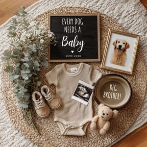 Pode incluir: Uma cena de anúncio de bebê com uma lousa com as palavras "EVERY DOG NEEDS A Baby" e "JUNE 2026". Inclui uma foto emoldurada de um golden retriever, um body bege, sapatos de bebê, uma ultrassonografia e uma tigela para cães com "BIG BROTHER!".