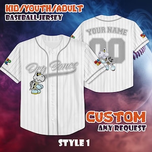May include: White baseball jersey with gray pinstripes, featuring a Dry Bones cartoon character and the text "Dry Bones." The jersey has a button-up front and short sleeves. The back of the jersey has the text "YOUR NAME" and the number "00."