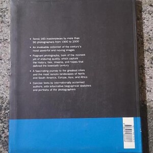 May include: A hardcover book with a black cover and a blue band at the bottom. The back of the book features text describing the contents, including 160 masterpieces by 90 photographers from 1900 to 2000.
