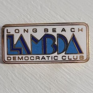 Może przedstawiać: Prostokątna przypinka ze złotą obwódką. Tekst brzmi "LONG BEACH" nad "LAMBDA DEMOCRATIC CLUB". Słowo "LAMBDA" jest niebieskie ze złotymi konturami na białym tle.