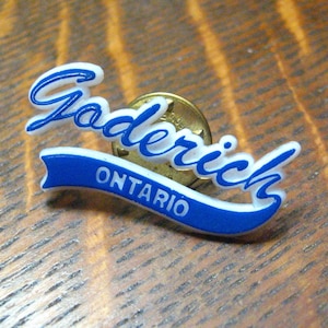 May include: Blue and white plastic pin with the text "Goderich ONTARIO" in a cursive font.