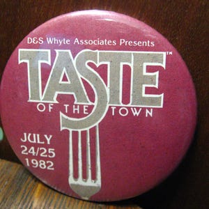 Puede incluir: Un botón rojo con texto blanco que dice "D&S Whyte Associates Presents Taste of the Town" con un gráfico de tenedor y las fechas "July 24/25 1982".