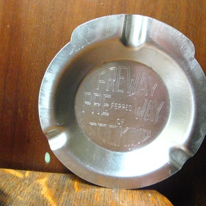 May include: A silver metal ashtray with the words "Preway Preferred of Cooking" engraved on the bottom.