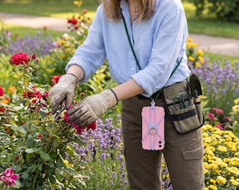 May include: A light blue button-down shirt, olive green cargo pants, and beige leather gardening gloves. A dark green lanyard holds a pink smartphone in a lavender silicone case with a ring stand. An olive green utility pouch contains garden shears and a small trowel.