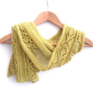 May include: A yellow knitted scarf with a lacy pattern, hanging on a wooden hanger.