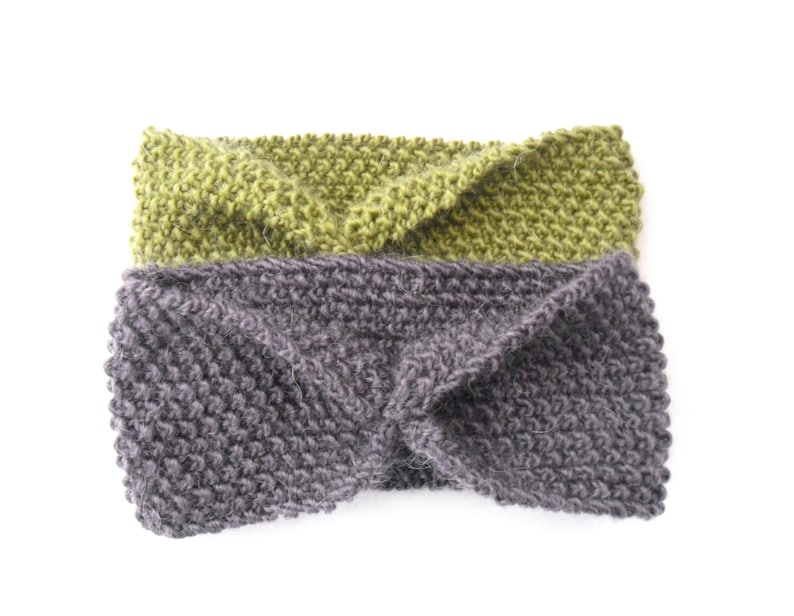 May include: Two knitted headbands. One is a muted green, the other is a dark gray. Both headbands are made of a thick, textured yarn and have a twisted design at the front. The headbands are displayed on a white background.