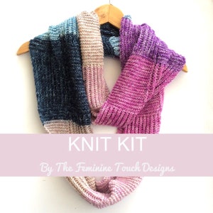 May include: Knit kit for a scarf in shades of pink, blue, and beige. The kit includes yarn and instructions. "Knit Kit By The Feminine Touch Designs" is written on a pink banner.