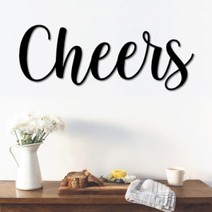 May include: Black wooden wall decor with the word "Cheers" in a cursive font.