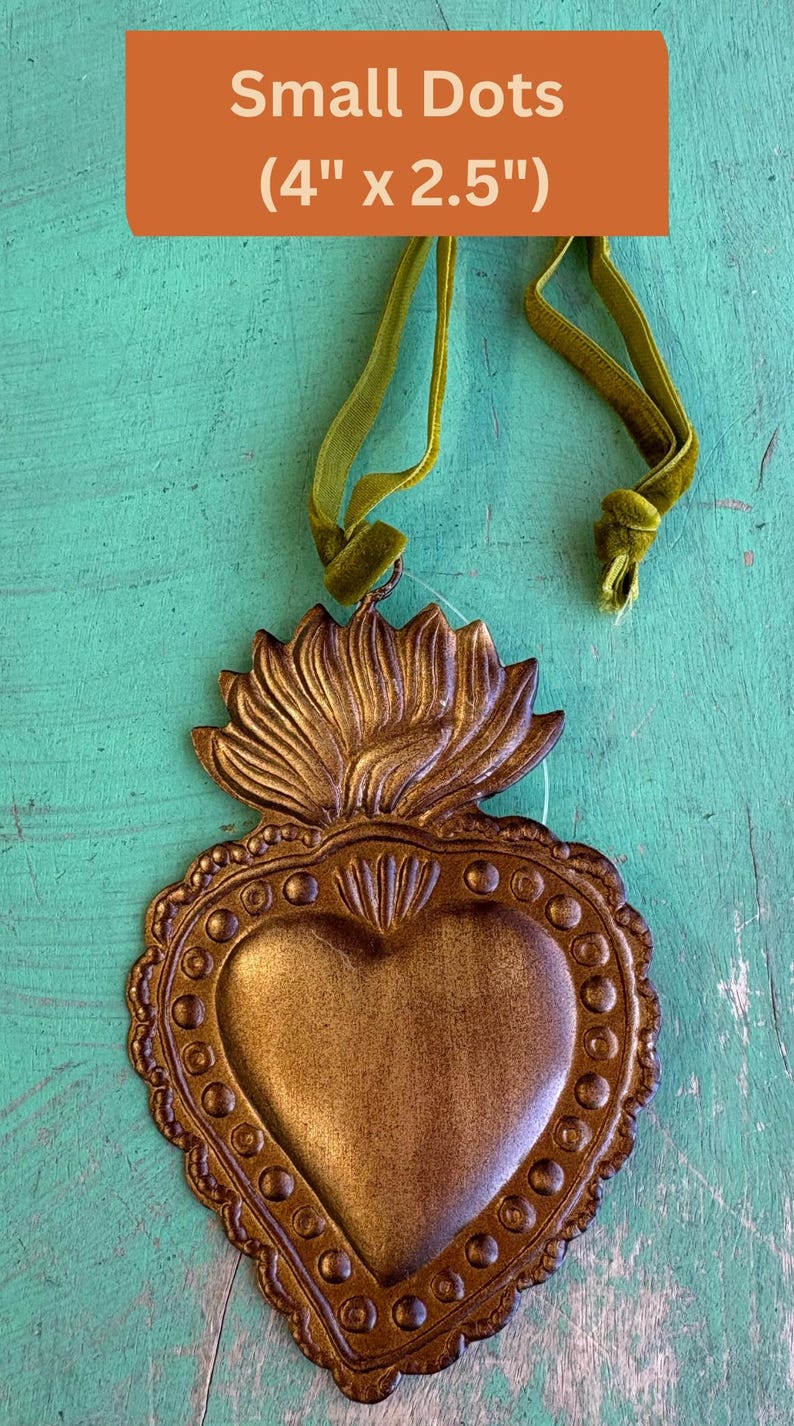 K&ouml;nnte beinhalten: Ein bronzefarbenes herzf&ouml;rmiges Ornament mit dekorativem Rand und floralem Aufsatz. Das Ornament ist ca. 10 cm x 6,3 cm gro&szlig; und hat ein gr&uuml;nes Samtband zum Aufh&auml;ngen. Der Text "Small Dots" wird auf orangefarbenem Hintergrund angezeigt.