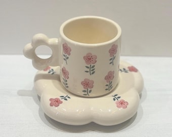 Alegre taza floral de cerámica hecha a mano con un portavasos con forma de flor.