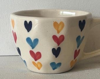 Taza de cerámica hecha a mano con varios corazones pequeños