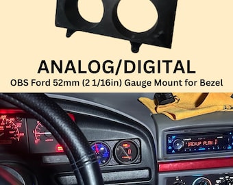 May include: Black plastic gauge mount with two circular openings. The text "ANALOG/DIGITAL" and "OBS Ford 52mm (2 1/16in) Gauge Mount for Bezel" are visible. The image also shows a car dashboard with gauges and a radio.
