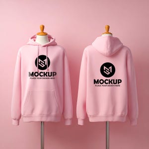 May include: Two light pink hoodies displayed on mannequins. Each hoodie has a black circular logo with a white design and the word "MOCKUP" with "PLACE YOUR DESIGN HERE" underneath. The hoodies are against a pink background.