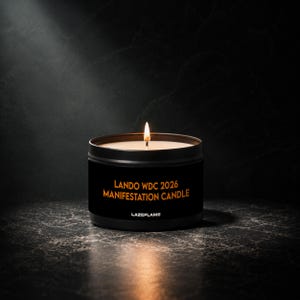 May include: A black metal tin candle with a lit wick and a label featuring the orange text LANDO WDC 2026 MANIFESTATION CANDLE and the brand name LAZEFLAME. The candle emits a warm glow from the flame, illuminating the dark container.