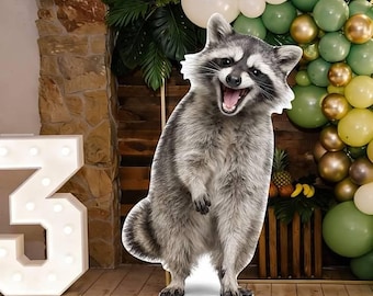 May include: A life-sized cardboard cutout of a standing raccoon with grey and black fur, a striped tail, and an open mouth showing teeth. The raccoon is positioned upright on its hind legs, displaying a detailed fur texture and a masked face.