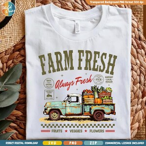 Może przedstawiać: Biały t-shirt z grafiką turkusowego pick-upa w stylu vintage przewożącego skrzynki z produktami. Napis głosi FARM FRESH, Always Fresh, 100% Fresh, Locally Grown, Support Local Dealer oraz FRUITS VEGGIES FLOWERS z obwódką w szachownicę.