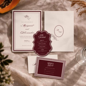 Könnte beinhalten: Ein Hochzeitspapeterie-Set bestehend aus einer cremefarbenen Einladung mit burgunderroten Rändern und einer Putten-Illustration, einer passenden burgunderroten Detailkarte mit gewelltem Rand und einer RSVP-Karte mit weißem Karomuster.