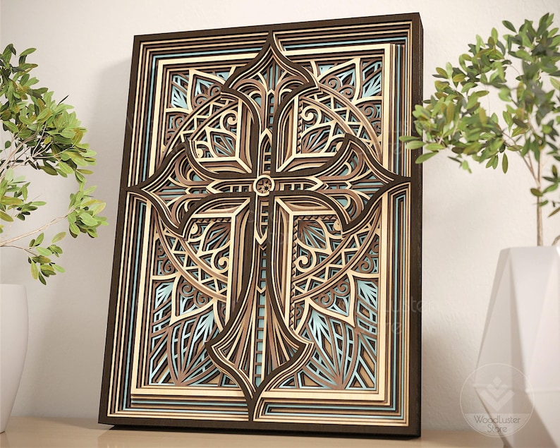 Puede incluir: Una obra de arte mural de madera en capas con un dise&ntilde;o detallado de cruz. La obra utiliza tonos de marr&oacute;n, beige y azul claro, creando un efecto tridimensional. La cruz est&aacute; centrada dentro de un marco rectangular.