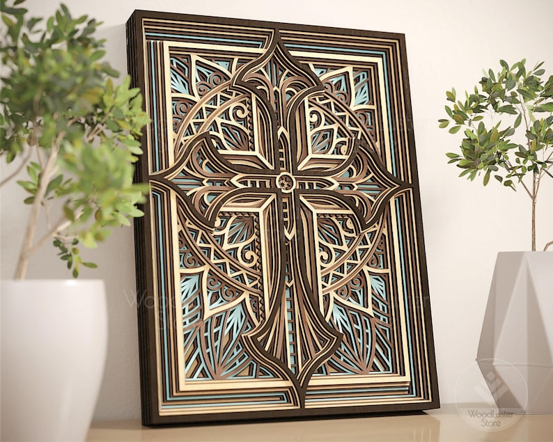 Puede incluir: Una obra de arte mural de madera en capas con un dise&ntilde;o de cruz detallado. La obra de arte incorpora varios tonos de marr&oacute;n, beige y azul claro, creando un efecto tridimensional. La cruz est&aacute; centrada dentro de un marco rectangular, mostrando patrones intrincados y formas geom&eacute;tricas.