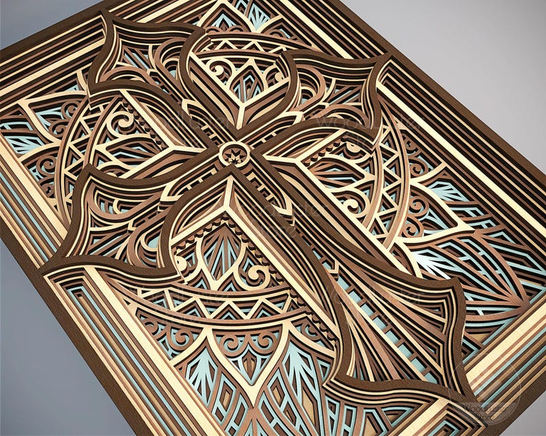Puede incluir: Una obra de arte de madera en capas con un dise&ntilde;o de cruz detallado. La obra utiliza varios tonos de marr&oacute;n, beige y azul claro, creando un efecto tridimensional. Se ven patrones intrincados y formas geom&eacute;tricas.