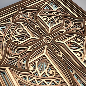 Puede incluir: Una obra de arte de madera en capas con un dise&ntilde;o geom&eacute;trico. La obra presenta un patr&oacute;n complejo de formas y l&iacute;neas entrelazadas en tonos de marr&oacute;n, beige y azul claro. El dise&ntilde;o es sim&eacute;trico y parece estar cortado con l&aacute;ser.