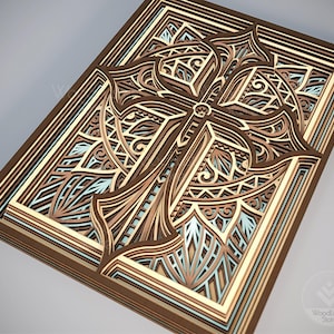 Puede incluir: Una obra de arte de madera en capas con un dise&ntilde;o detallado de cruz. La obra utiliza varios tonos de marr&oacute;n, beige y azul claro para crear profundidad y dimensi&oacute;n. La cruz est&aacute; intrincadamente cortada con patrones decorativos.