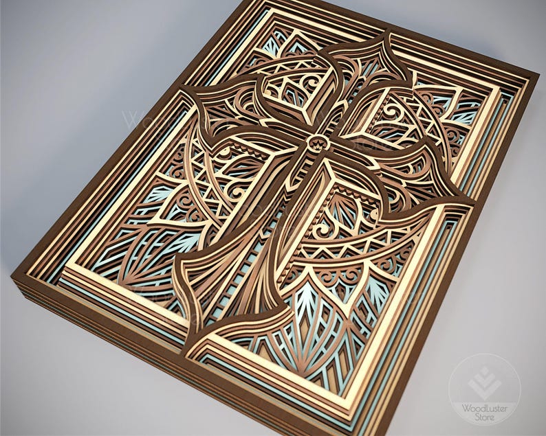 Puede incluir: Una obra de arte de madera en capas con un dise&ntilde;o detallado de cruz. La obra utiliza varios tonos de marr&oacute;n, beige y azul claro para crear profundidad y dimensi&oacute;n. La cruz est&aacute; intrincadamente cortada con patrones decorativos.