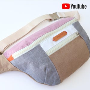 May include: A multi-colored fabric fanny pack with a zippered pocket and a brown leather label that says "Bagtique".