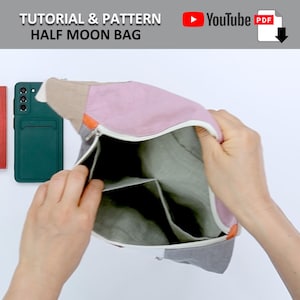 May include: A half moon bag with a zipper closure and multiple compartments. The bag is made of a light gray fabric with a pink and beige fabric flap. The bag is open and a hand is reaching inside.