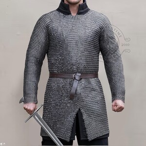 May include: A silver chainmail shirt with long sleeves and a black collar. A brown leather belt is worn around the waist. The person is holding a silver sword. The shirt is a historical garment.