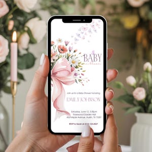 May include: A smartphone displays a baby shower invitation. The design features a pink bow, floral arrangements, and butterflies. Text includes "BABY in bloom" and details for Emily Johnson's shower: date, time, location, and RSVP information.