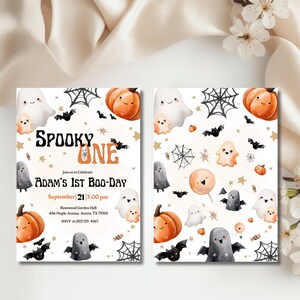 May include: Halloween party invitation with the text "SPOOKY ONE" and "ADAM'S 1ST BOO-DAY". The design features cartoon ghosts, pumpkins, bats, and spiderwebs in orange, black, and white. Includes event details.
