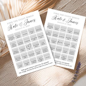 May include: Two white wedding bingo cards with the text "Find the Guest Bingo" and the names "Kate & James" with the date "August 11, 2025". The cards have various prompts for guests to fill in. A lavender sprig is in the background.