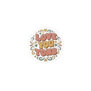 May include: A circular sticker featuring the phrase "LOVE YOU TONS" in a retro font. The text is in pink, yellow, and brown, with green and yellow hearts and swirls around the words.
