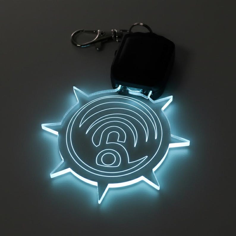 May include: A glowing, clear acrylic keychain with a stylized wifi symbol design. The keychain has a starburst shape with pointed edges and a silver clasp. A black remote is attached to the keychain.