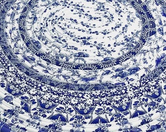 May include: A circular rug constructed from coiled fabric strips featuring a blue and white floral pattern. The design consists of concentric rings of fabric stitched together, displaying various botanical motifs including flowers and leaves.