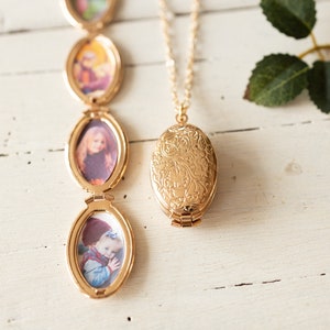 May include: A gold locket necklace with a floral design. The locket has a small photo inside. The necklace is on a white surface.