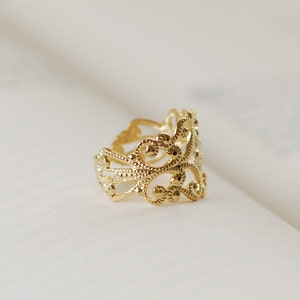 Puede incluir: Un anillo de filigrana dorado con un dise&ntilde;o delicado e intrincado. El anillo est&aacute; hecho de un metal delgado y tiene una forma ligeramente redondeada.