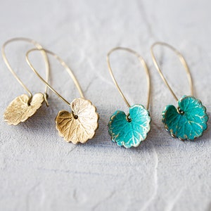 Op de afbeelding: Een paar gouden en turquoise oorringen in de vorm van een blad met delicate draadlussen. De oorringen zijn gemaakt van metaal en hebben een getextureerd oppervlak.