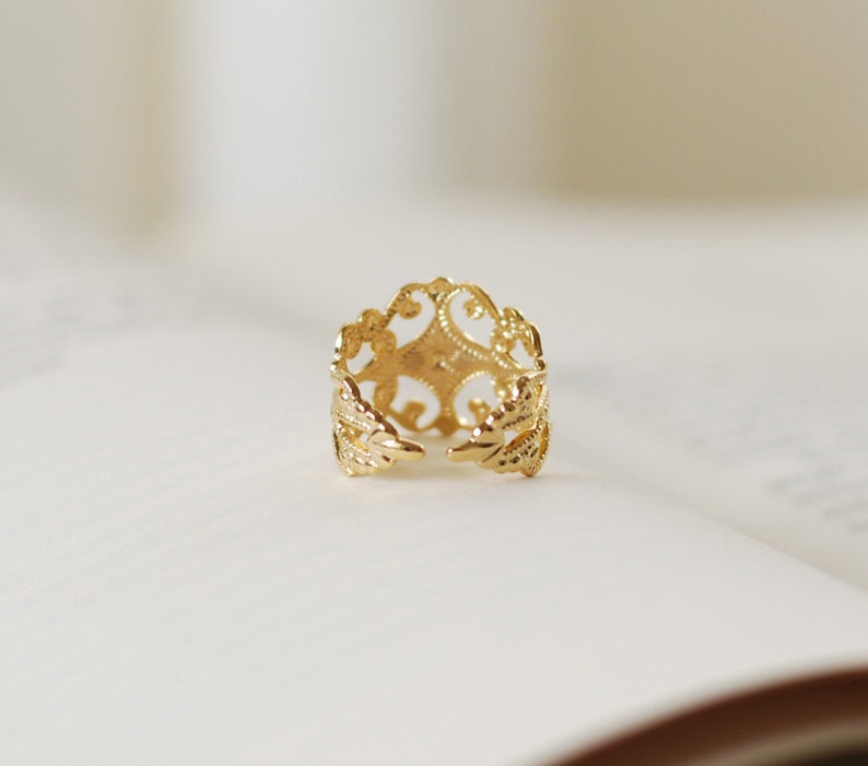 Puede incluir: Un anillo de filigrana dorado con un dise&ntilde;o delicado e intrincado. El anillo es abierto y ajustable para adaptarse a diferentes tama&ntilde;os de dedos.